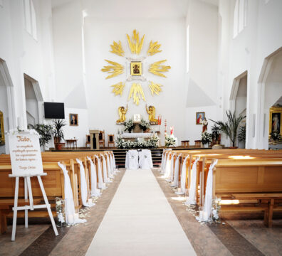 dekoracja ławek w kościele, biały dywan, płatki róż, cylindry szklane ze świecami