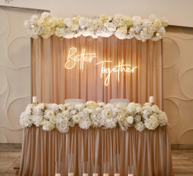 dekoracja stolika pary młodej, ścianka na wesele, beżowe materiały, białe kwiaty, ledon better together