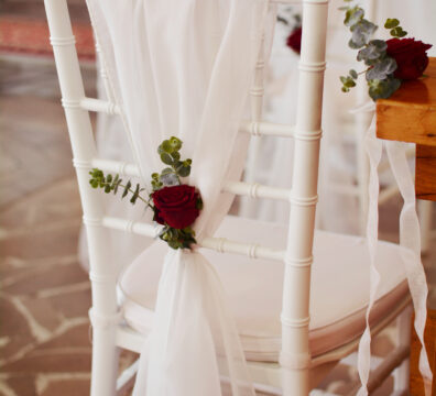 Bordowa dekoracja kościoła na ślub. Białe krzesła chiavari