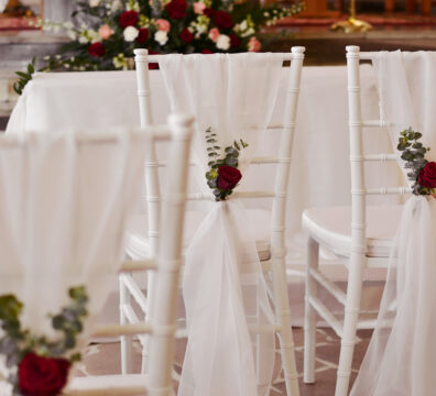 Bordowa dekoracja kościoła na ślub. Białe krzesła chiavari