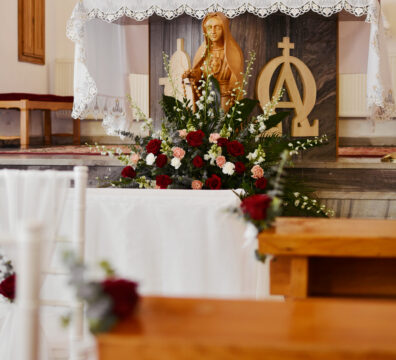 Bordowa dekoracja kościoła na ślub. Białe krzesła chiavari